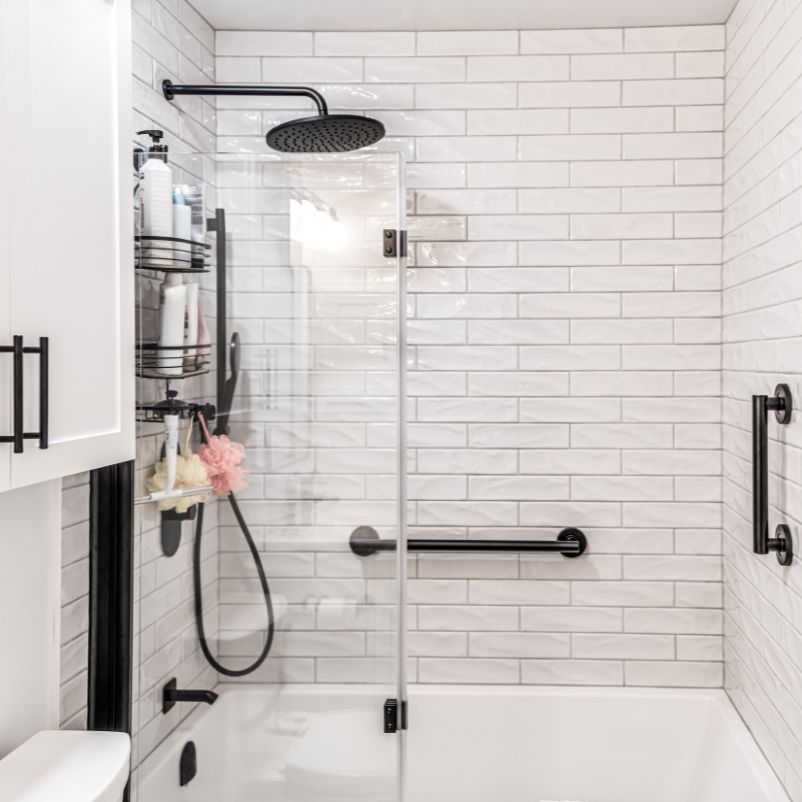 White modern bathroom renovation with glass shower and subway tiles.