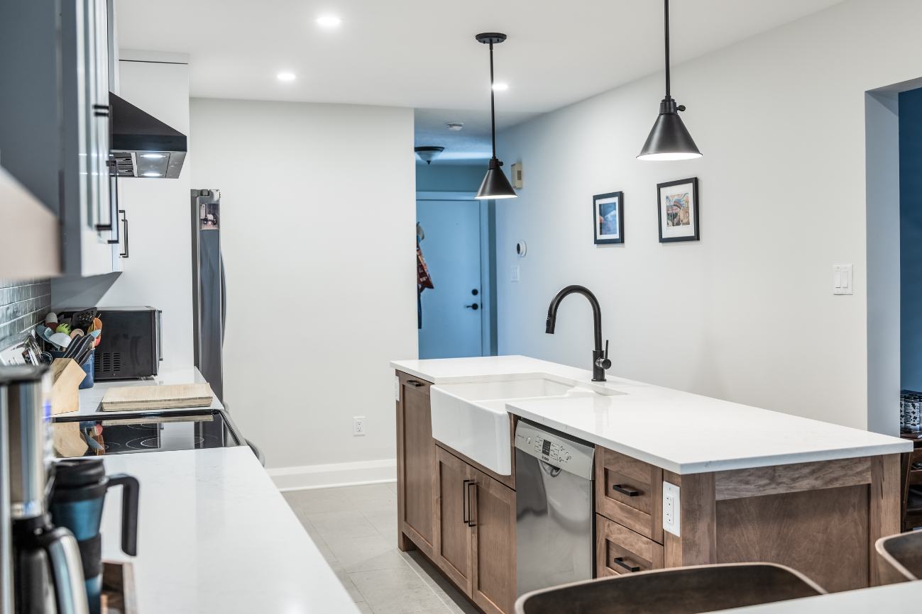 Renovated kitchen shot from corner beside stools, facing wood-cabinet island.