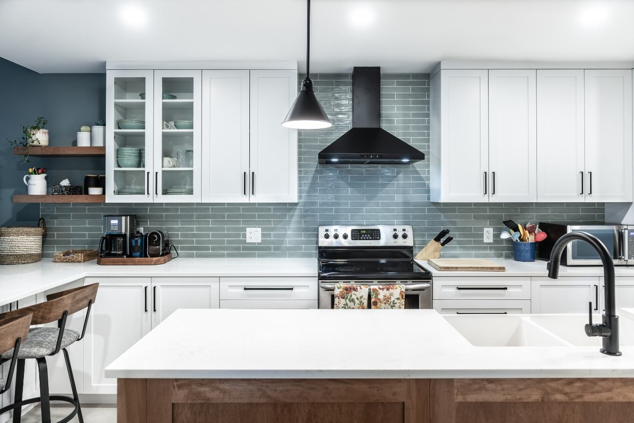 Renovated kitchen looking over island with sink towards the stove and black hood fan.