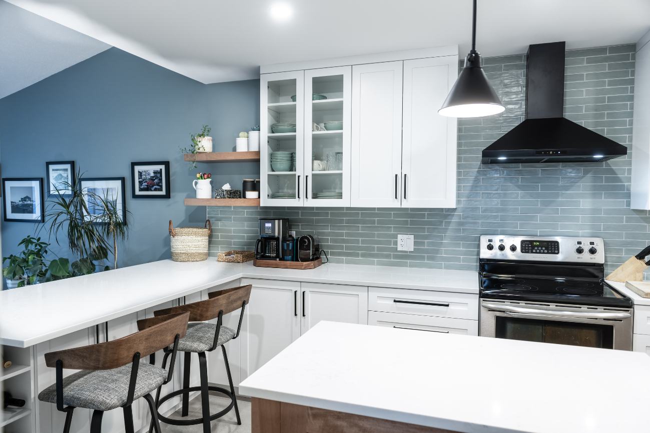 Shot of renovated kitchen from behind island sink showcasing light blue backsplash.