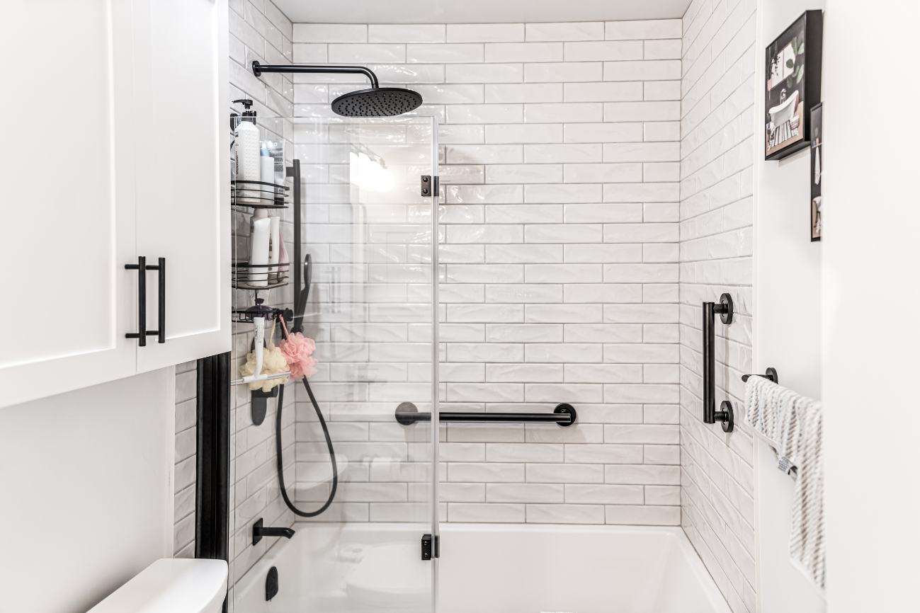 Renovated white modern bathroom facing shower with glass partition. 