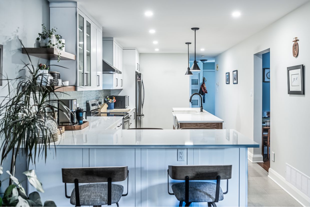 Shot of renovated kitchen from behind countertop chairs.