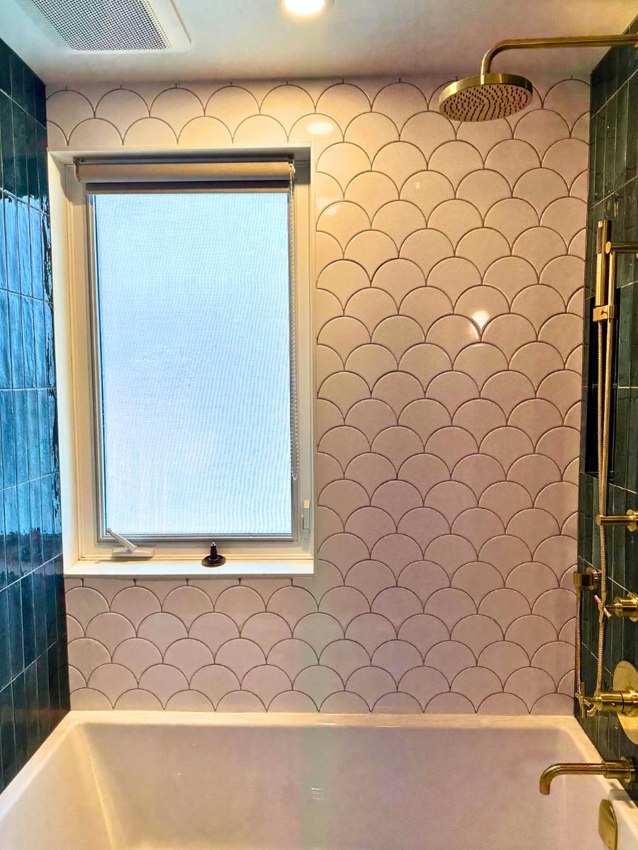 Window in renovated shower with white mermaid tiles.