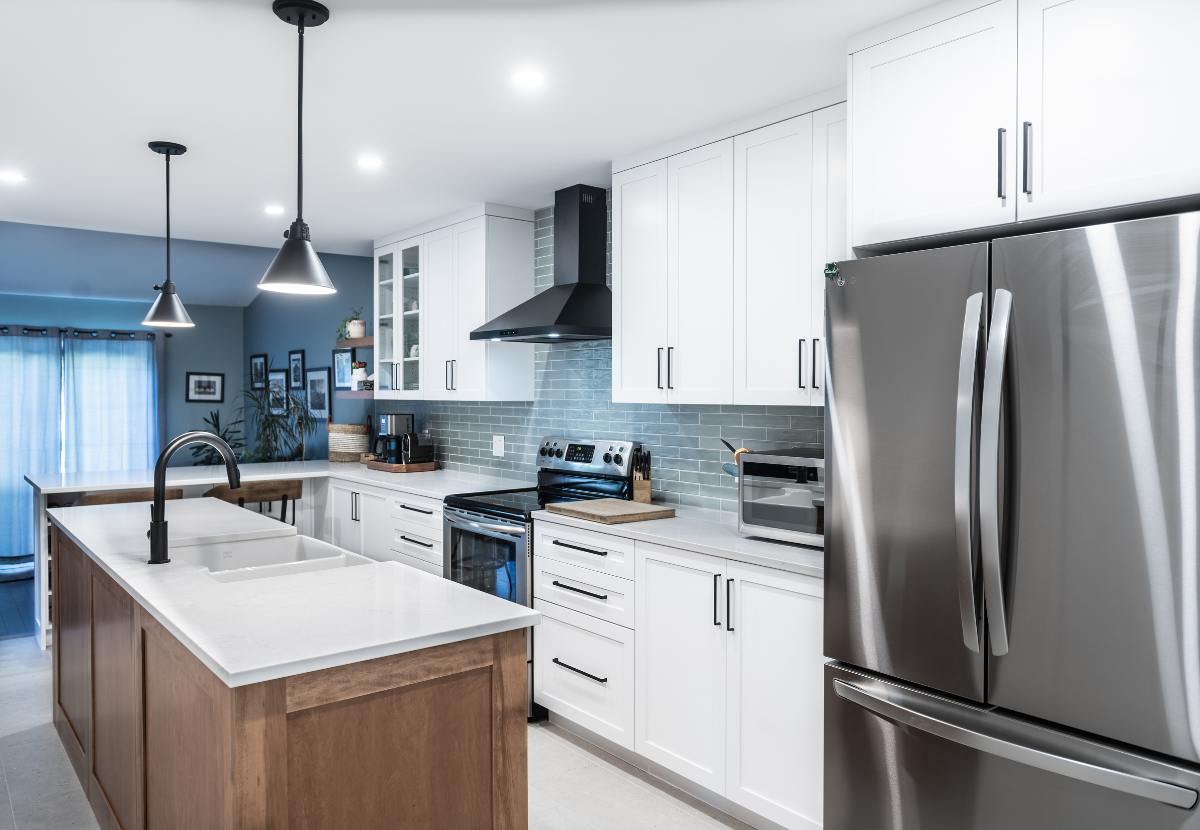 Renovated kitchen shot from beside island. White cabinets and oak island.