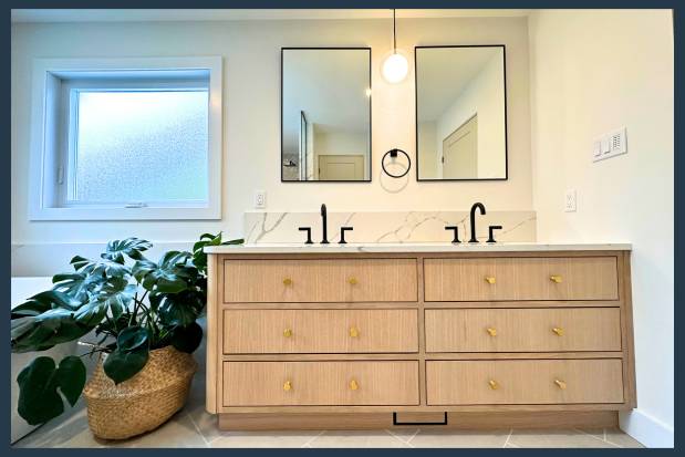 Renovated bathroom vanity with natural wood, double mirrors and large plant beside.